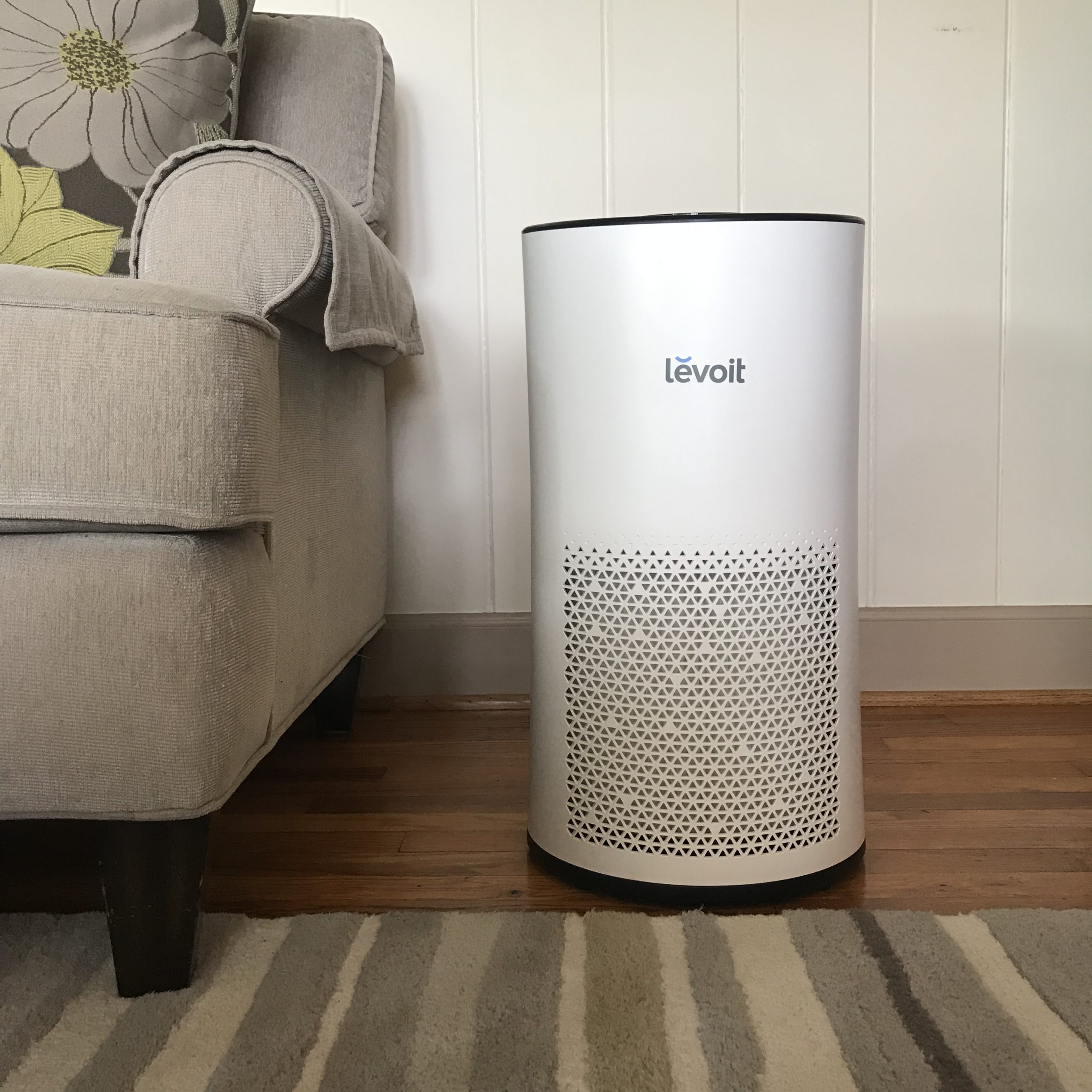 Purificador de aire en un salón junto a un sofá