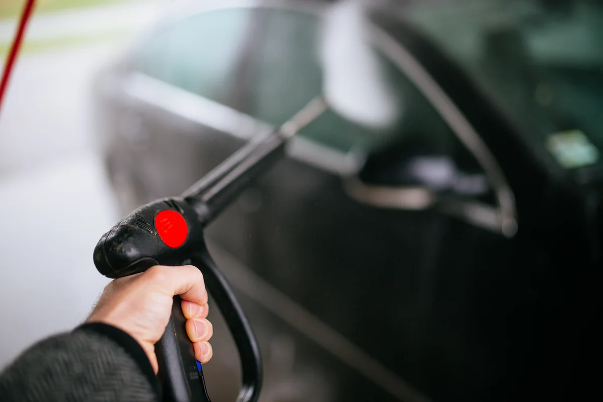 Persona limpiando un coche con una hidrolavadora
